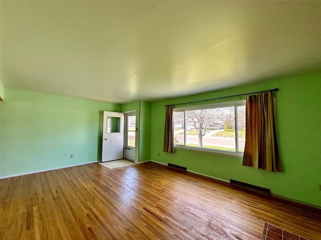 empty room featuring visible vents, baseboards, and wood finished floors