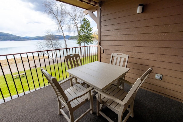 balcony featuring a water view and outdoor dining area