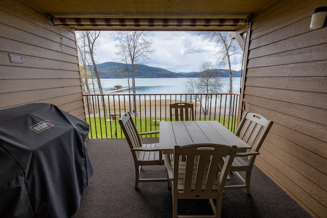 balcony with area for grilling, outdoor dining space, and a water and mountain view