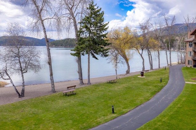 view of home's community featuring a water and mountain view and a yard