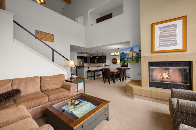 living area with an inviting chandelier, a fireplace, a high ceiling, stairway, and carpet