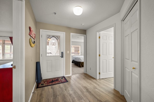 entrance foyer with baseboards, a textured ceiling, and light wood finished floors