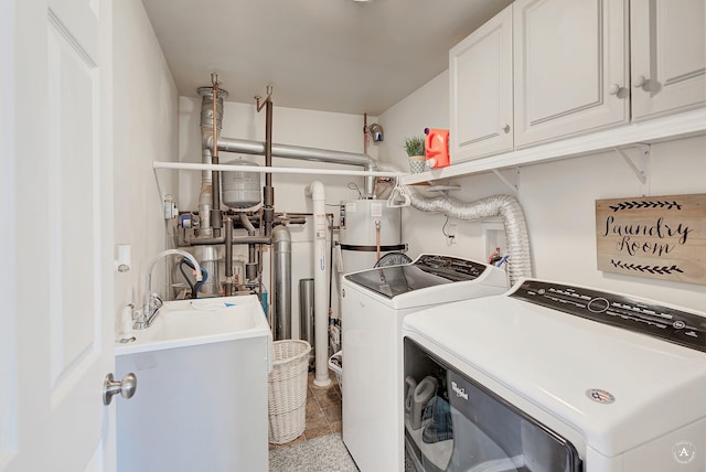 washroom with a sink, water heater, independent washer and dryer, and cabinet space