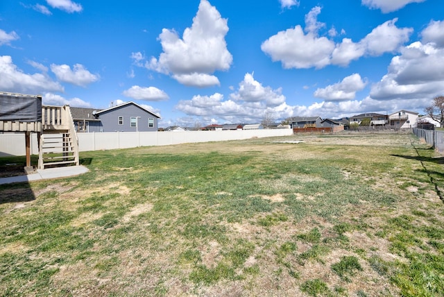 view of yard with a fenced backyard, stairway, and a residential view