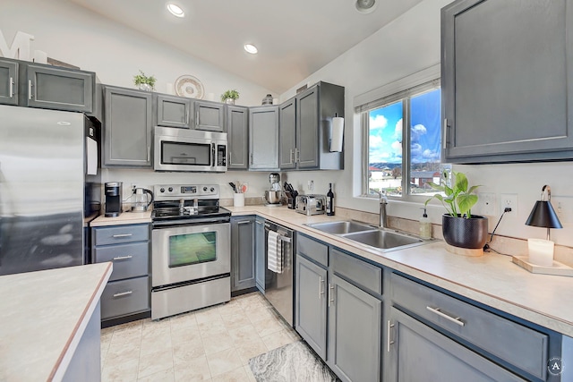 kitchen with lofted ceiling, recessed lighting, light countertops, a sink, and appliances with stainless steel finishes