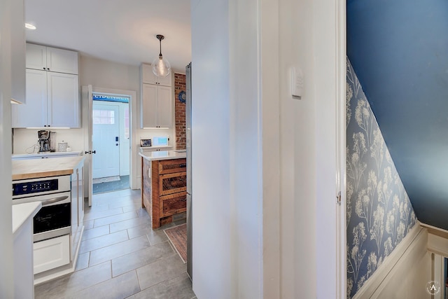 615 Dearborn Ave Unit 320Power, St, Helena, MT 59601 - kitchen with white cabinets, hanging light fixtures, wood counters, stainless steel oven, and light tile patterned floors