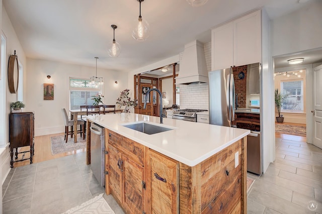 615 Dearborn Ave Unit 320Power, St, Helena, MT 59601 - kitchen featuring a sink, stainless steel appliances, custom range hood, tasteful backsplash, and a center island with sink