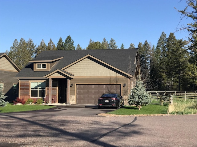 craftsman inspired home featuring an attached garage, fence, a front lawn, and aphalt driveway