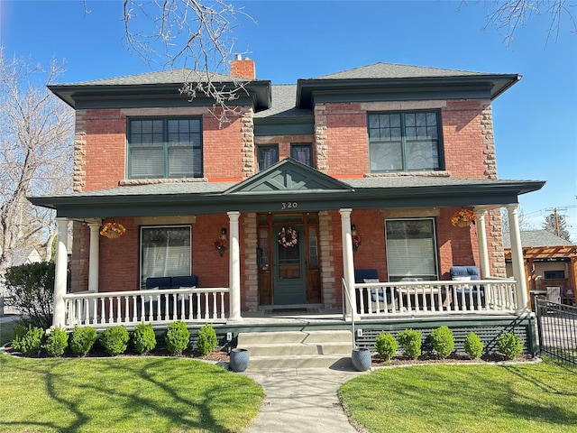 view of front of house featuring a porch, brick siding, and a chimney