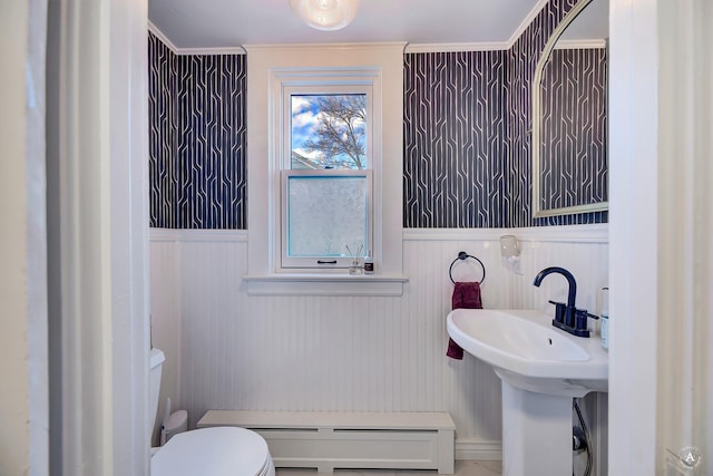 half bathroom featuring toilet, baseboard heating, and a wainscoted wall