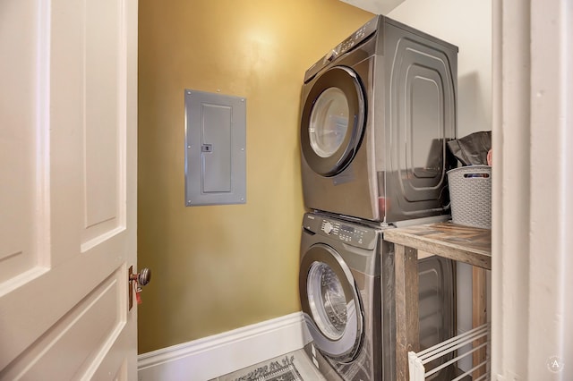 clothes washing area featuring stacked washer and clothes dryer, laundry area, and electric panel