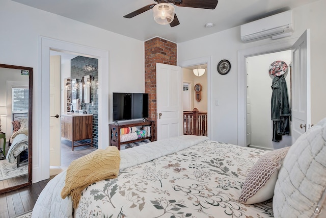 bedroom featuring connected bathroom, a wall mounted air conditioner, wood-type flooring, a ceiling fan, and a closet