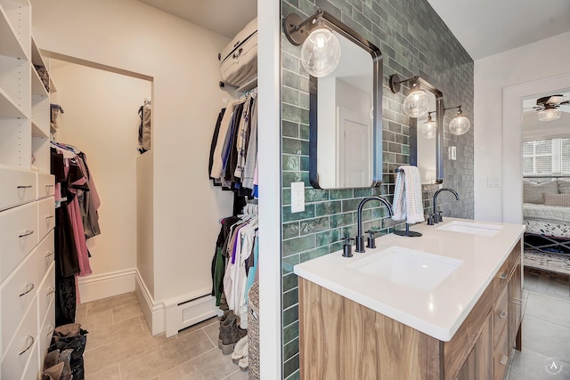 bathroom featuring double vanity, a walk in closet, a sink, and tile patterned flooring
