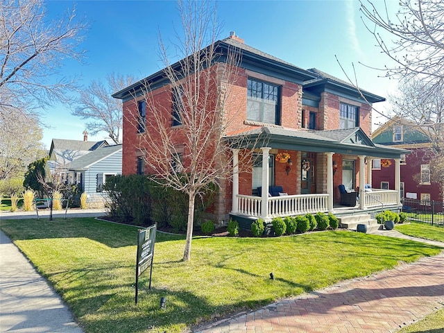 italianate home featuring fence, a front yard, a porch, and brick siding