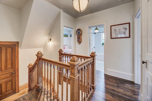hallway with baseboards, dark wood finished floors, and an upstairs landing
