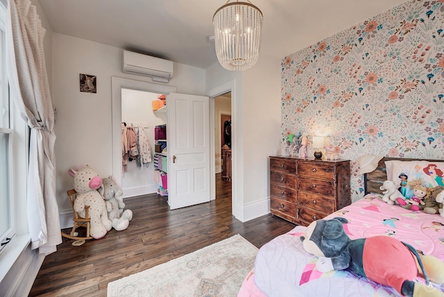 bedroom with baseboards, a chandelier, a wall unit AC, and wood finished floors