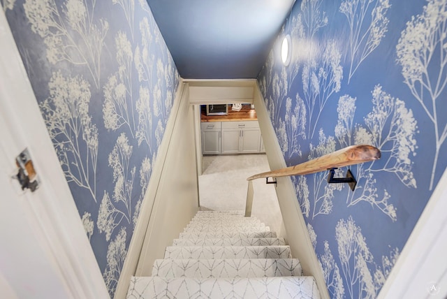 staircase featuring carpet flooring and wallpapered walls