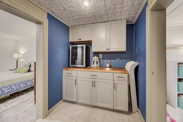 kitchen with butcher block countertops, baseboards, an ornate ceiling, and light carpet