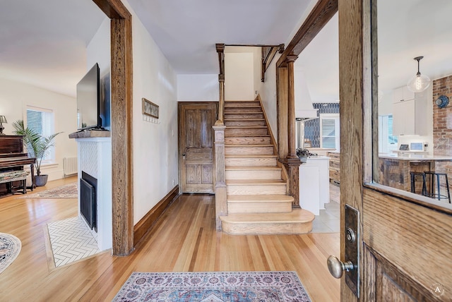 stairway with a fireplace with flush hearth and wood finished floors