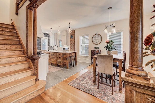 dining area featuring ornate columns, stairs, and light wood-type flooring