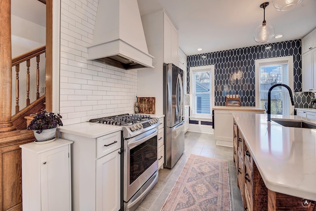 kitchen featuring appliances with stainless steel finishes, tasteful backsplash, a sink, premium range hood, and light countertops