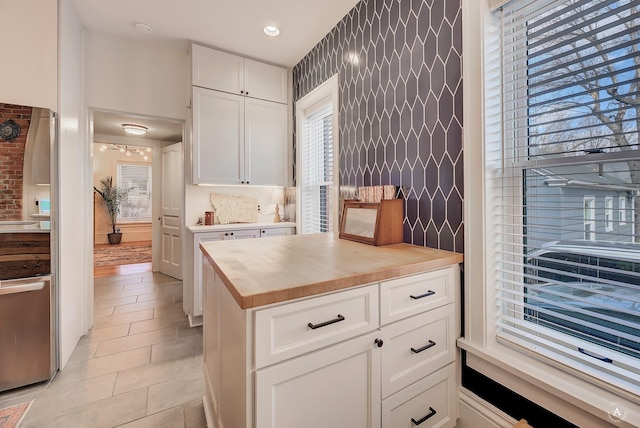 kitchen with butcher block countertops, an accent wall, white cabinetry, recessed lighting, and light tile patterned floors