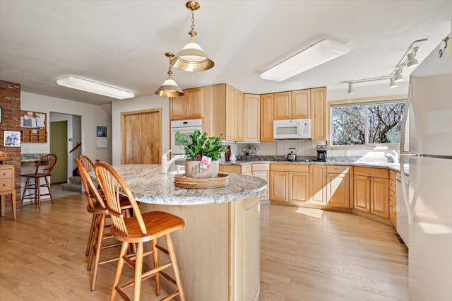 kitchen featuring light wood-type flooring, light brown cabinetry, and white appliances