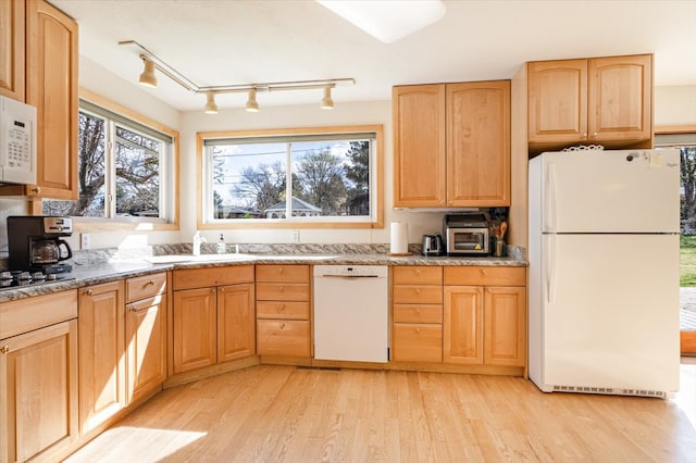 kitchen with light brown cabinetry, rail lighting, a sink, light wood finished floors, and white appliances