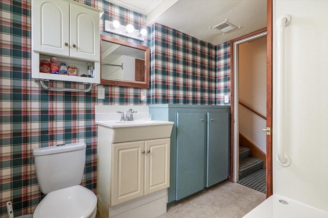 bathroom featuring vanity, toilet, wallpapered walls, and visible vents