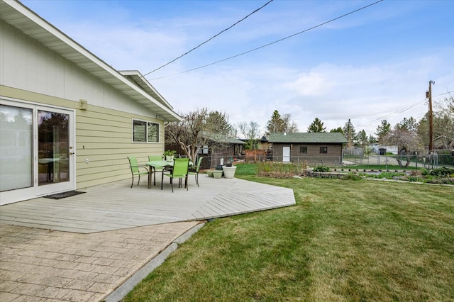 view of yard featuring fence, a wooden deck, and outdoor dining space