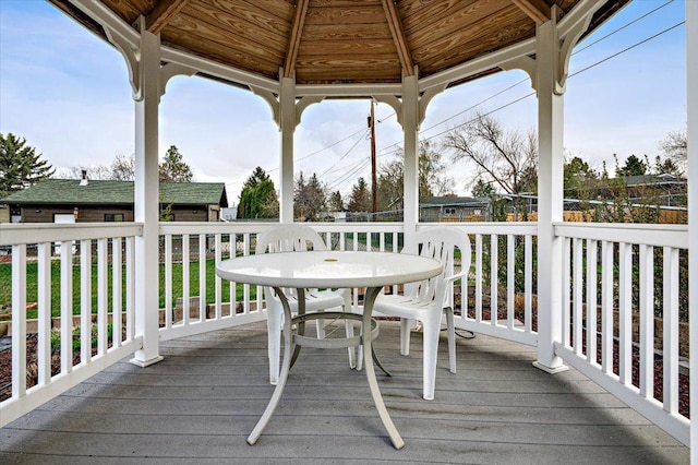 wooden terrace with outdoor dining area and a gazebo