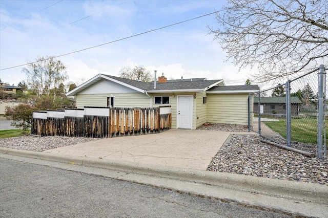 single story home with a fenced front yard, driveway, and a chimney