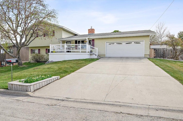 tri-level home with a garage, a front lawn, covered porch, a chimney, and driveway