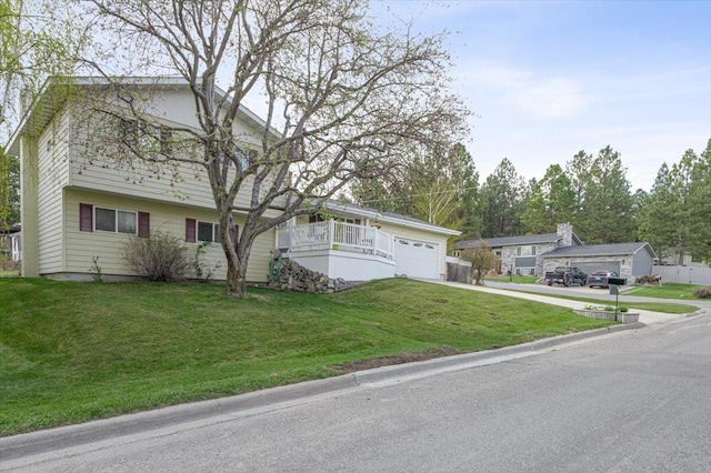 split level home featuring an attached garage, concrete driveway, and a front yard