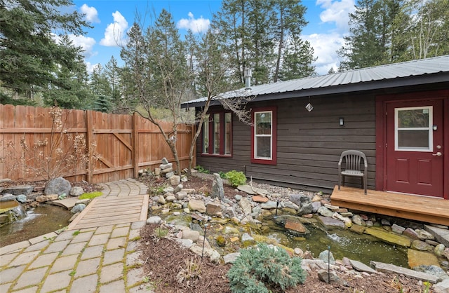 exterior space featuring fence, metal roof, and a small pond