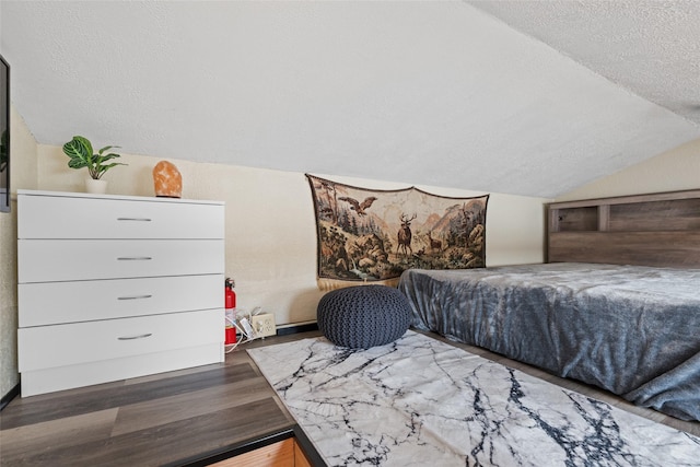 bedroom featuring a textured ceiling, wood finished floors, and vaulted ceiling