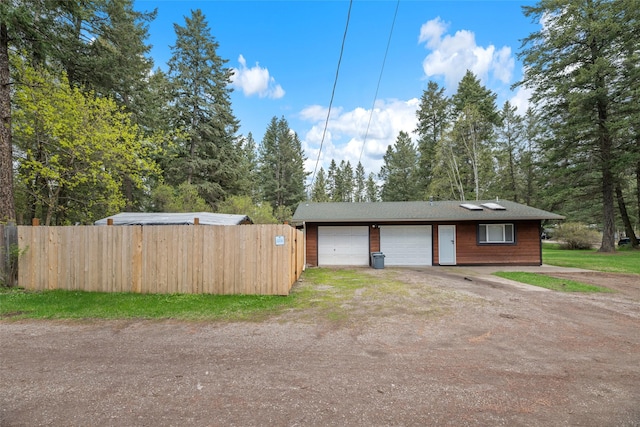 garage with fence and dirt driveway