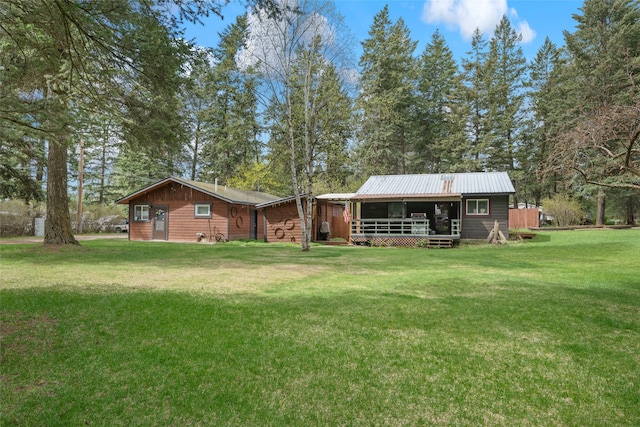 back of house featuring metal roof, a yard, and a deck