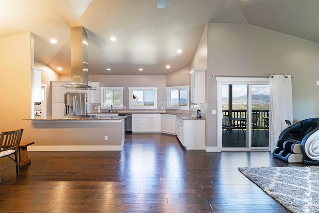 kitchen with a peninsula, dark wood-style floors, stainless steel fridge, island exhaust hood, and a sink