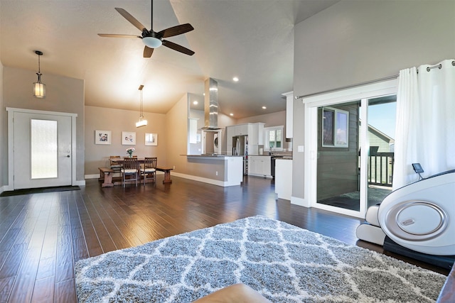 living room featuring ceiling fan, vaulted ceiling, baseboards, and dark wood-type flooring