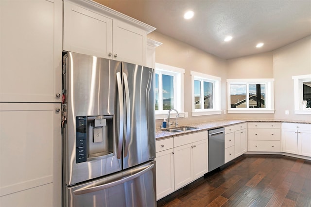 kitchen featuring dark wood-type flooring, a sink, light stone counters, and stainless steel appliances