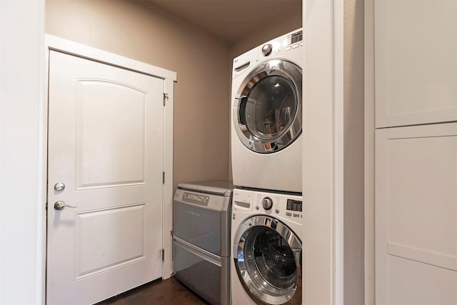 laundry area with laundry area, stacked washer / dryer, and dark wood-style floors