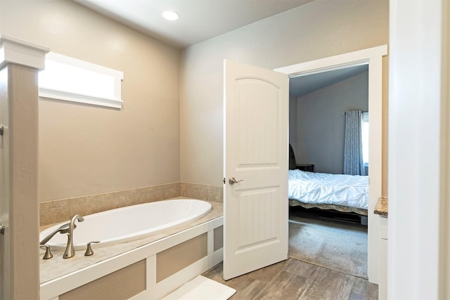 bathroom featuring ensuite bathroom, a garden tub, and wood finished floors