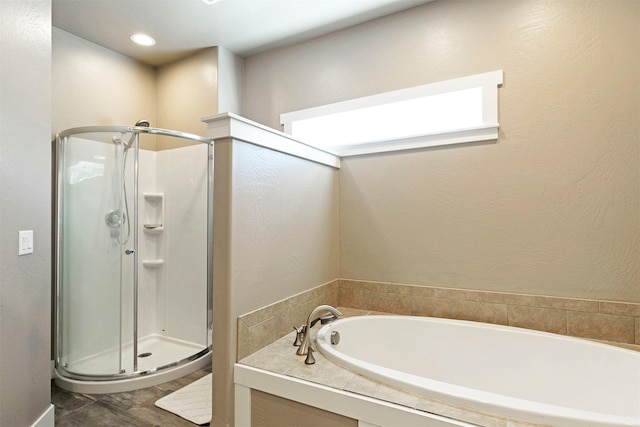 full bath with a textured wall, a stall shower, and a garden tub