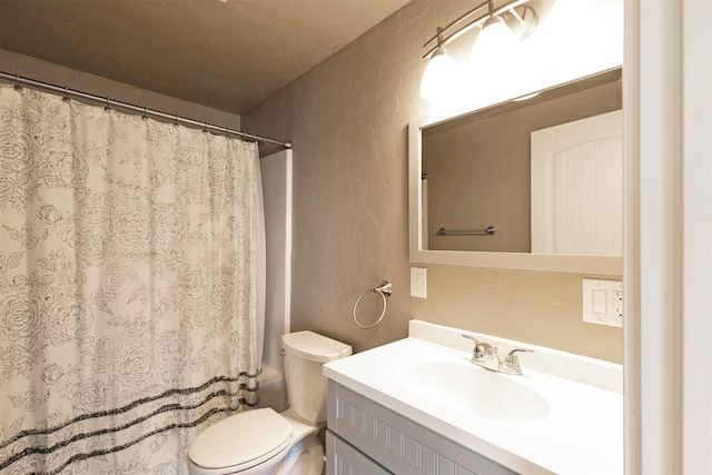 full bath with vanity, a textured wall, toilet, and shower / tub combo