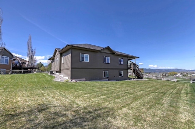 back of house featuring a yard, fence, a mountain view, and stairs