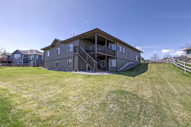 rear view of house featuring a lawn, a wooden deck, fence, and stairway