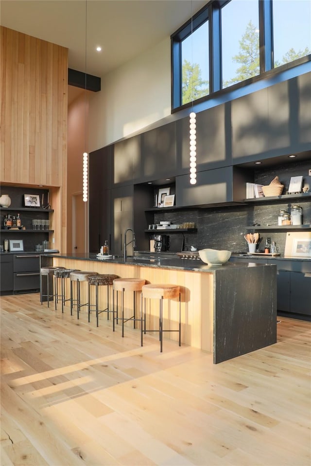 kitchen featuring dark countertops, a breakfast bar, modern cabinets, a high ceiling, and backsplash