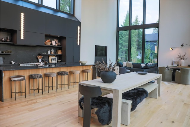dining room with light wood finished floors and a towering ceiling