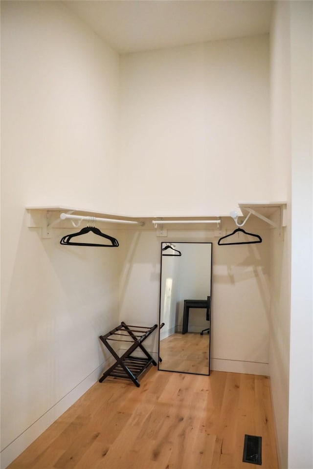 walk in closet with light wood-style floors